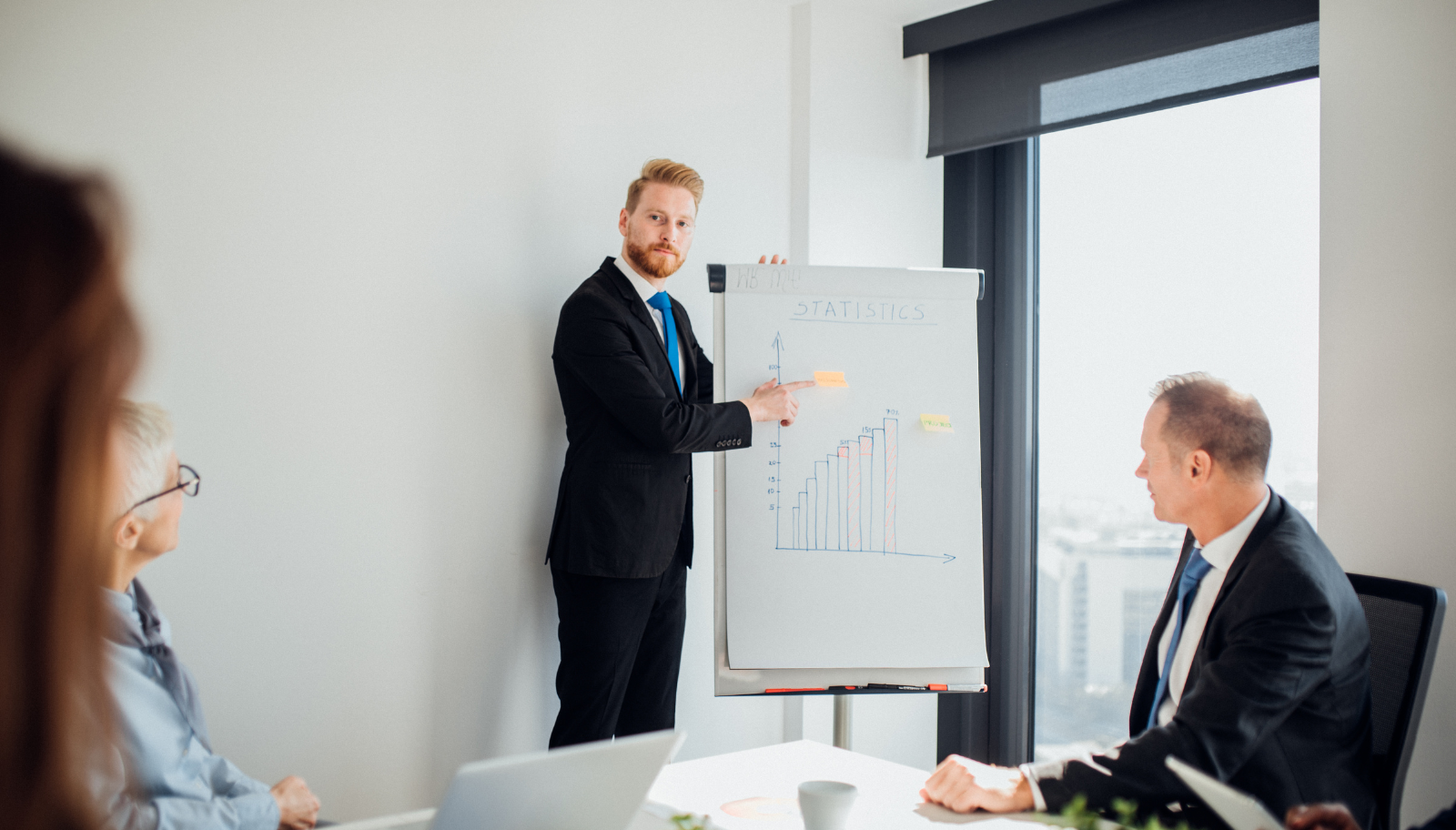 Presenter showing a bar chart of statistics on a flip chart during a hotel team meeting