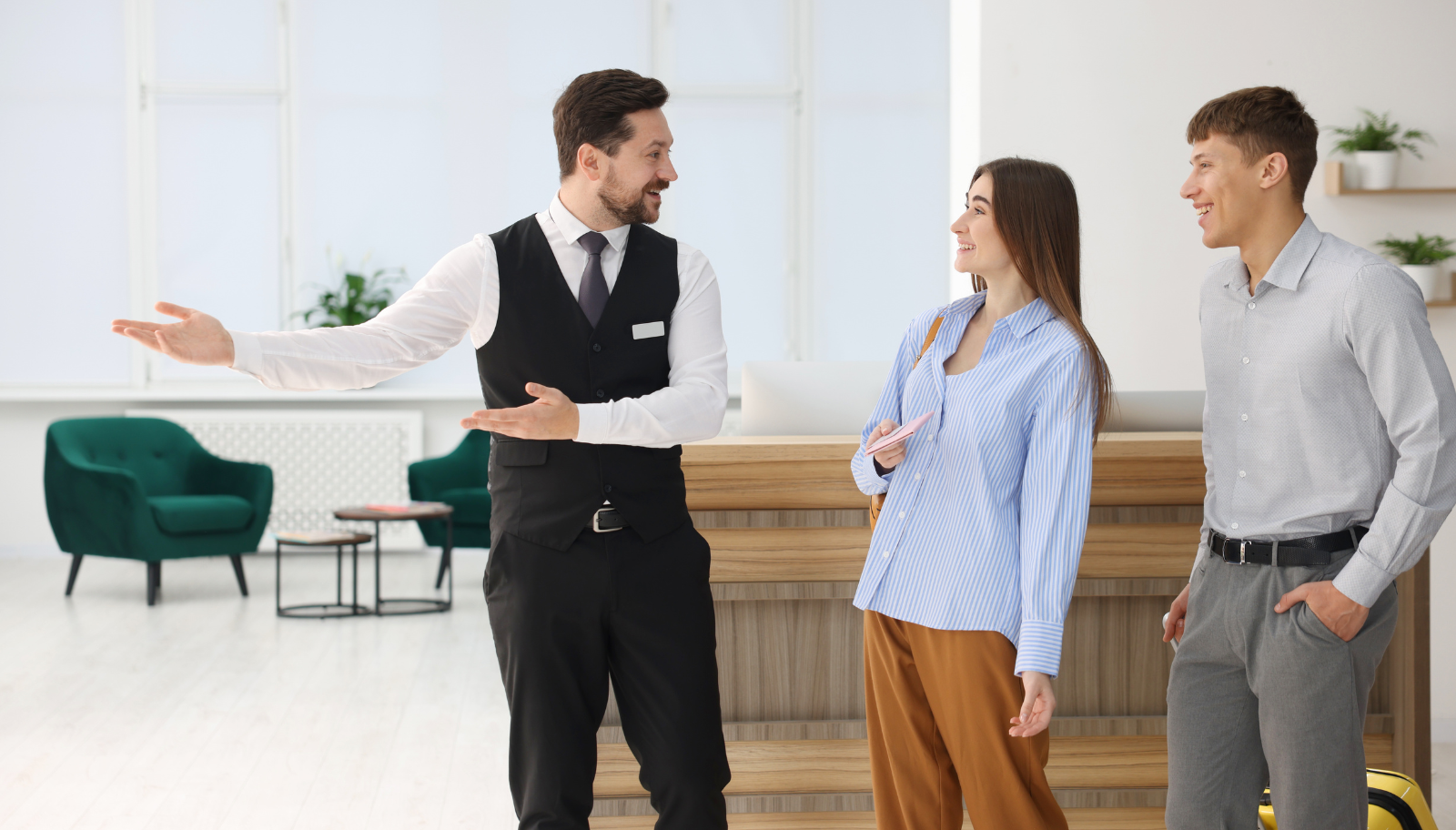 Hotel staff member personally welcoming two smiling guests in the lobby